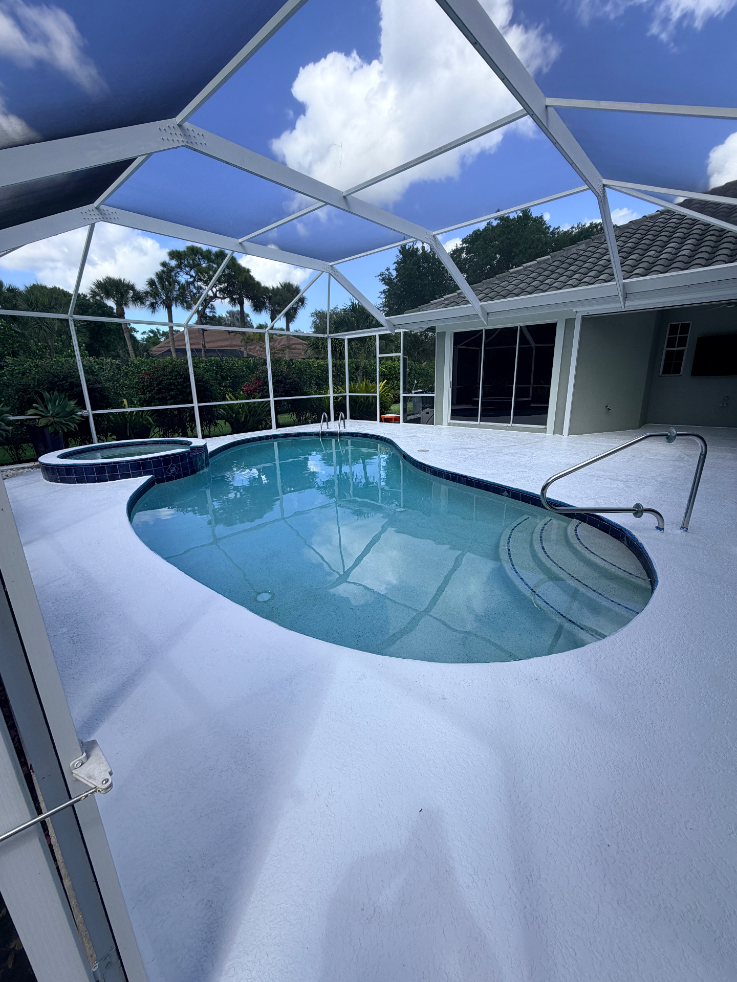 Completed white epoxy pool deck with screen enclosure